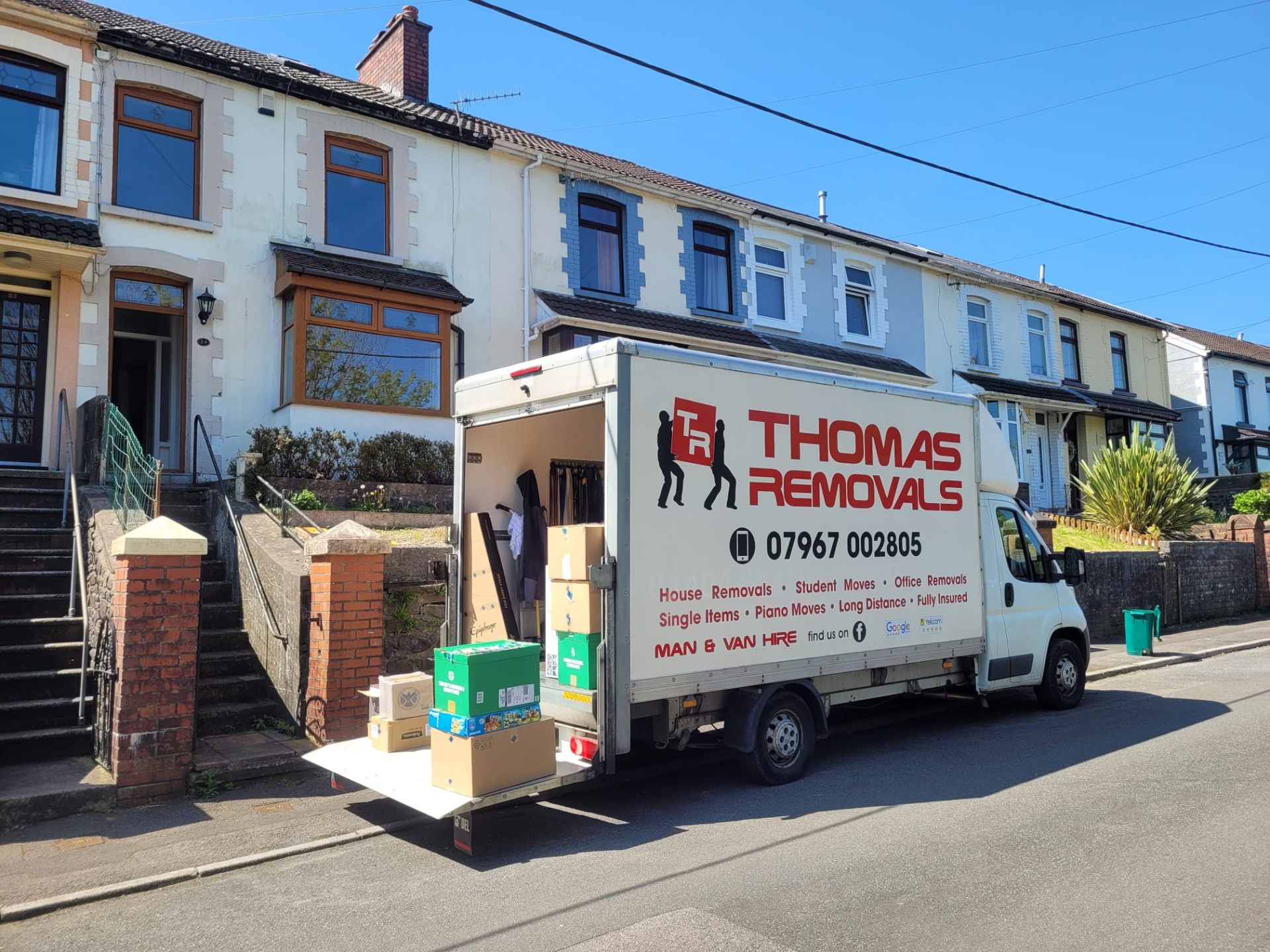 Thomas Removals van loaded with boxes and belongings outside a terraced house in Porth