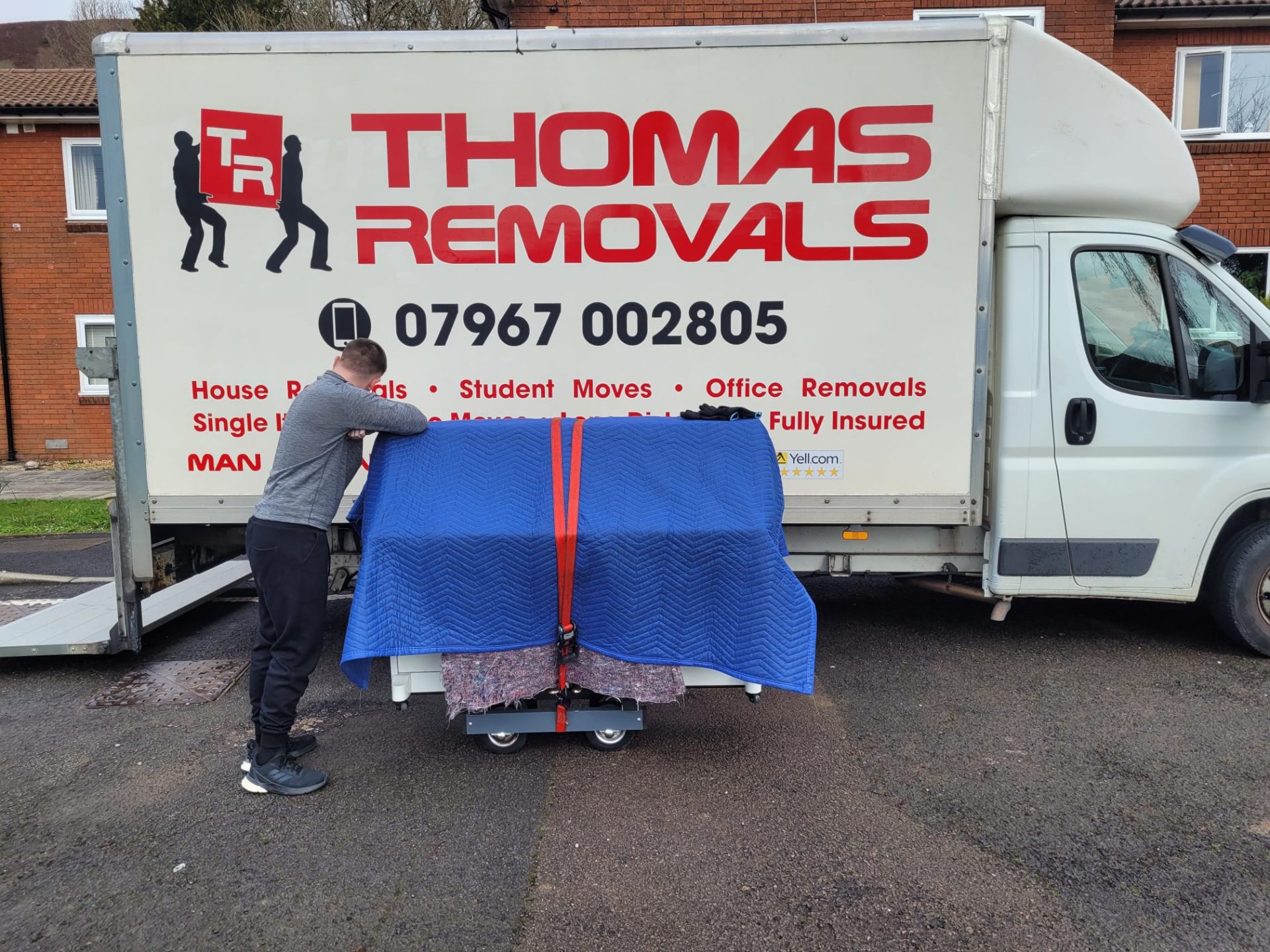 Thomas Removals team member carefully handling a wrapped piano for specialist piano removal
